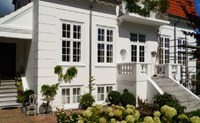 Husets facade er færdigmalet i kølig hvid farve, hvilket skaber et stilrent udtryk.